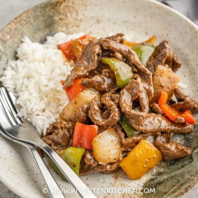 stir fried beef with bell peppers and black pepper sauce on top of rice