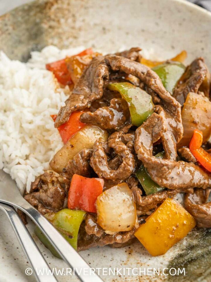 stir fried beef with bell peppers and black pepper sauce on top of rice