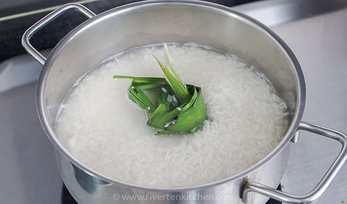 Glutinous rice with pandan leaves cooking in a pot.