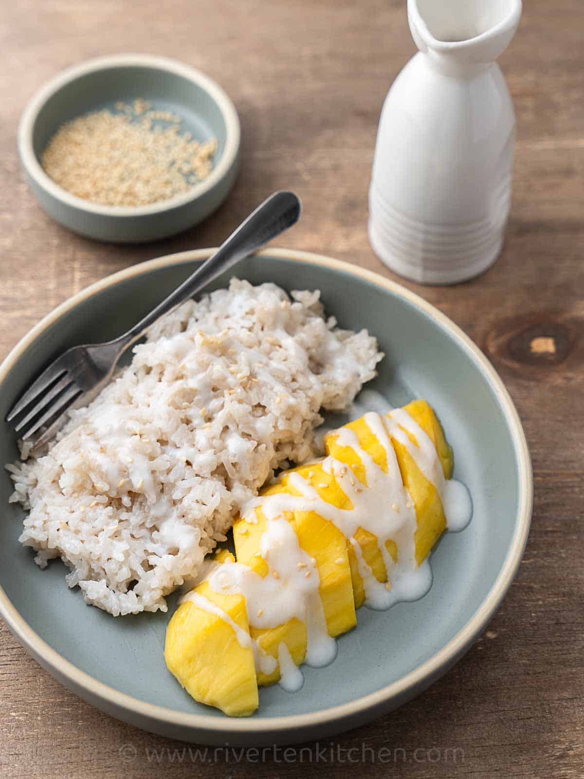 Glutinous rice with mango and coconut sauce in a light blue plate.