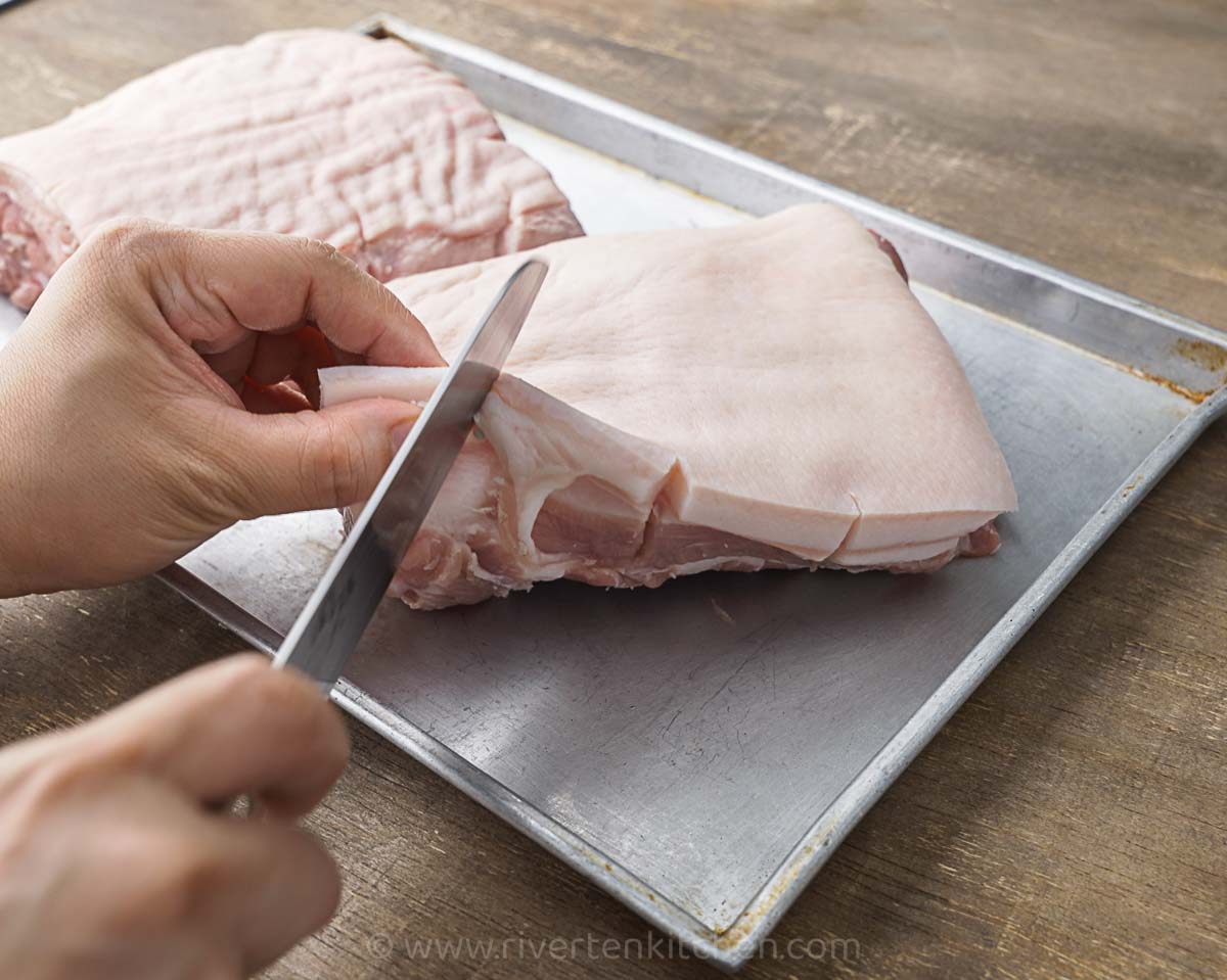 raw pork belly with slits on the side to prevent it from curling.