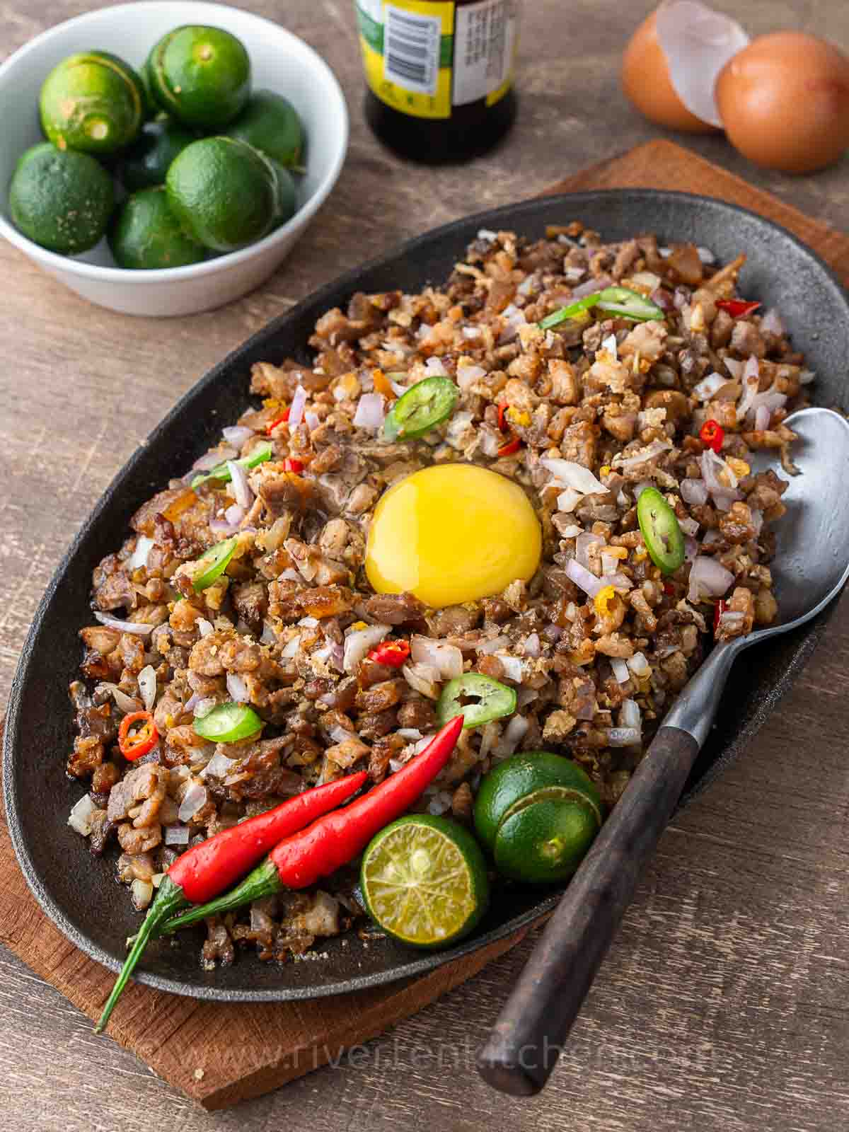 Filipino pork dish called sisig made of pork belly, onions, chilies served on a sizzling plate.