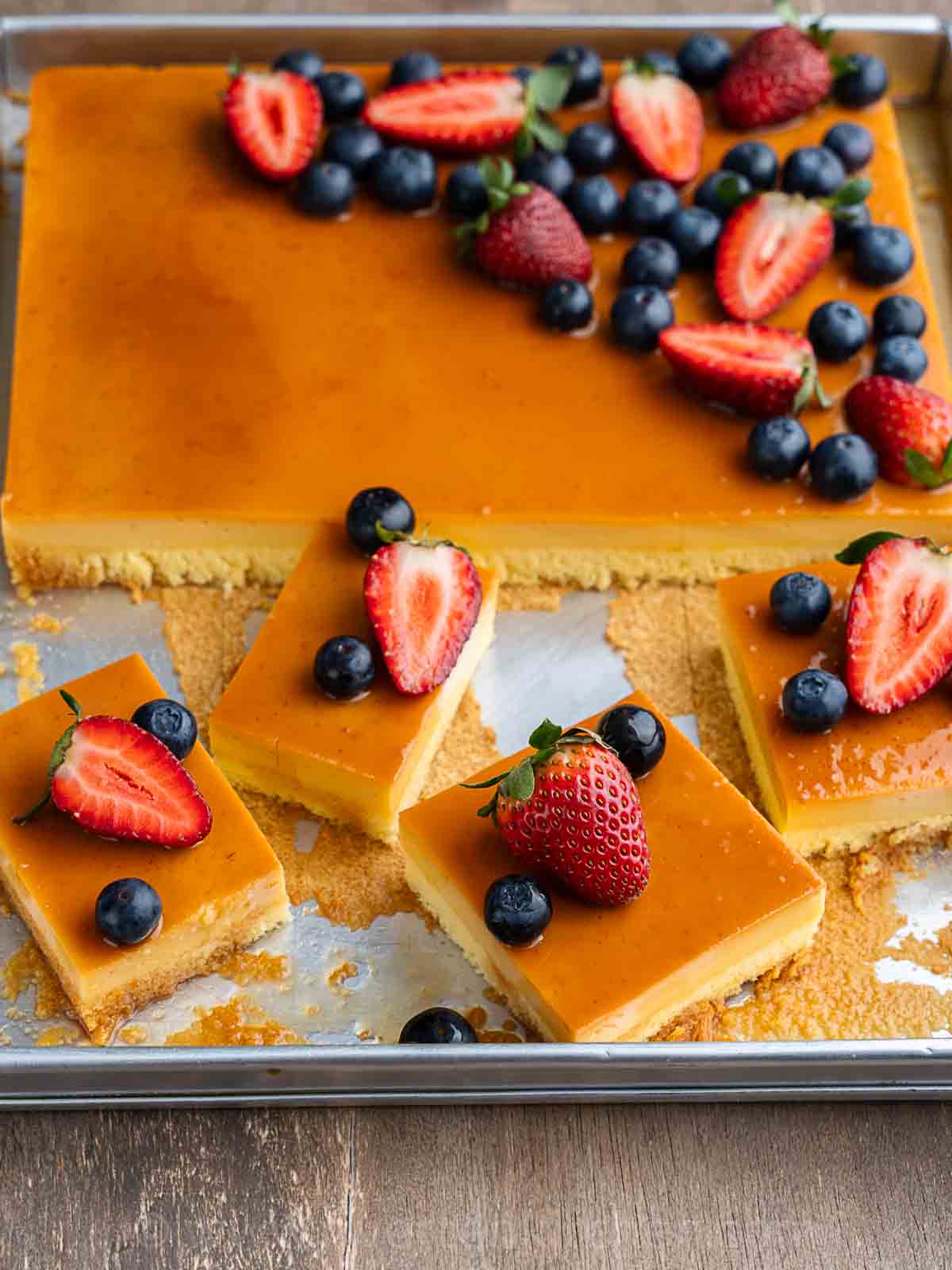 layers of cake made of custard or flan and chiffon cake topped with blueberries and strawberries.