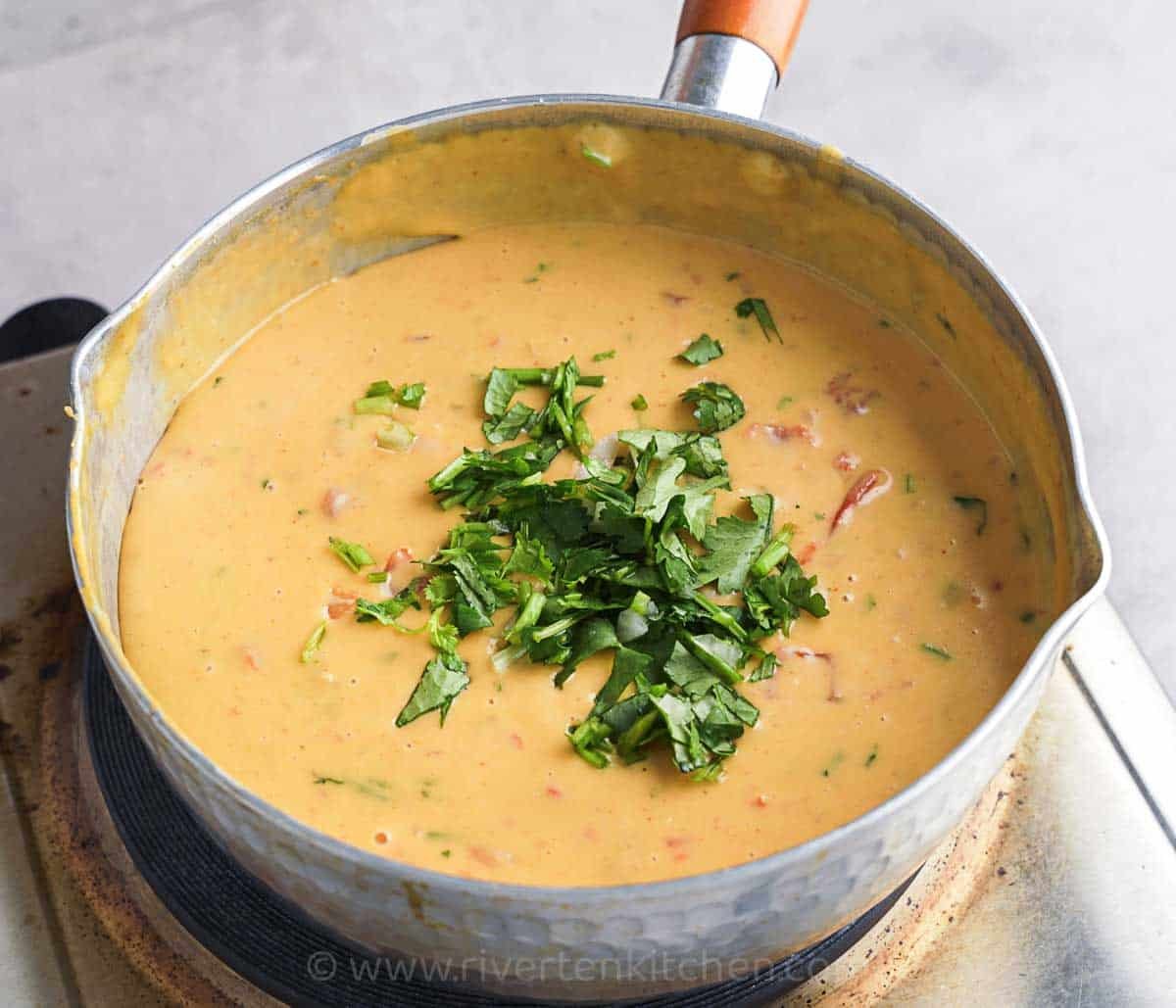 Cheese sauce with coriander in a pot.