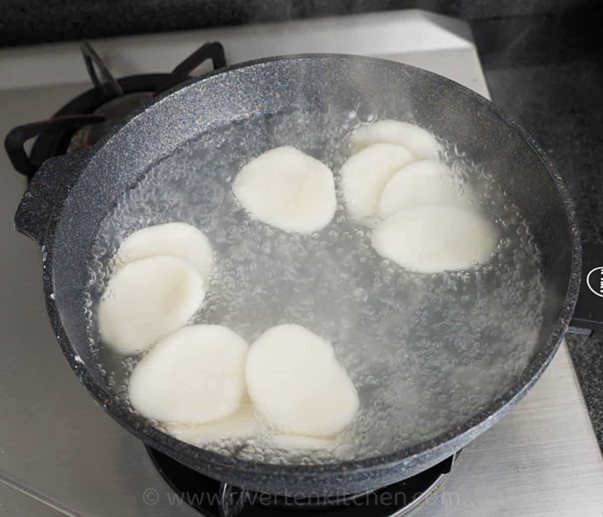 flat glutinous rice cake called palitaw cooking in boiling water.